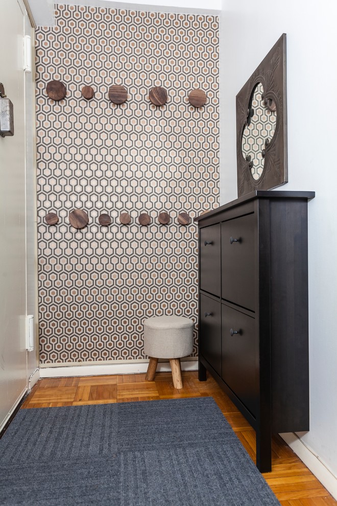 Entryway - small transitional medium tone wood floor entryway idea in New York with a white front door
