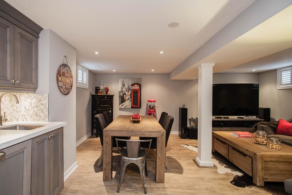 Large transitional look-out basement in Toronto with grey walls, medium hardwood floors, no fireplace and brown floor.