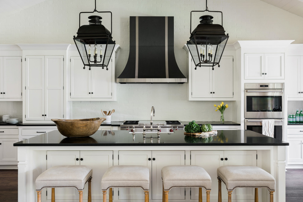 Design ideas for a large country u-shaped open plan kitchen in Atlanta with a farmhouse sink, flat-panel cabinets, white splashback, brick splashback, stainless steel appliances, dark hardwood floors, with island and brown floor.