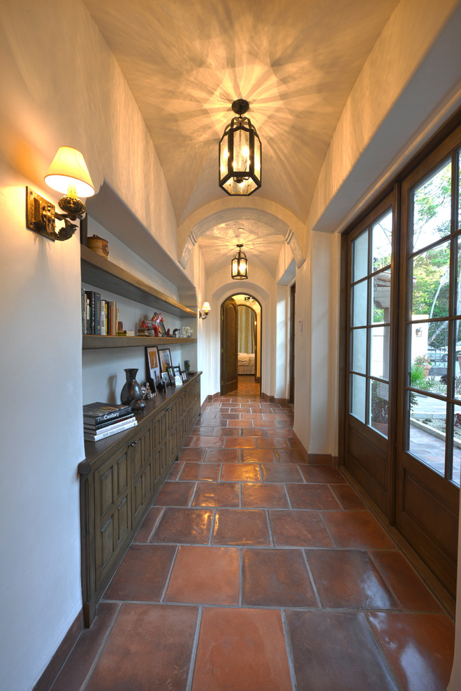This is an example of a large mediterranean hallway in San Francisco with red floor, beige walls and terra-cotta floors.