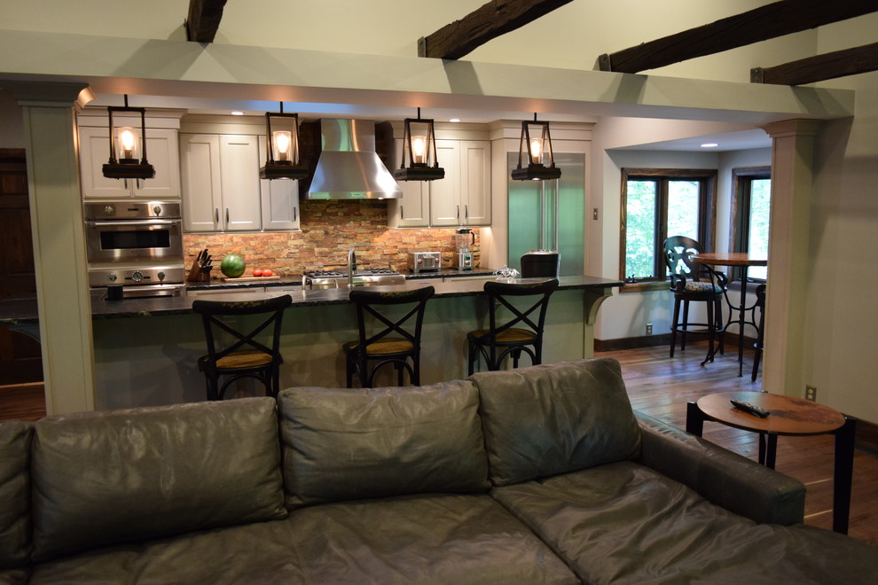 Large transitional galley medium tone wood floor kitchen photo with an undermount sink, recessed-panel cabinets, white cabinets, quartz countertops, multicolored backsplash, stone slab backsplash, stainless steel appliances and an island