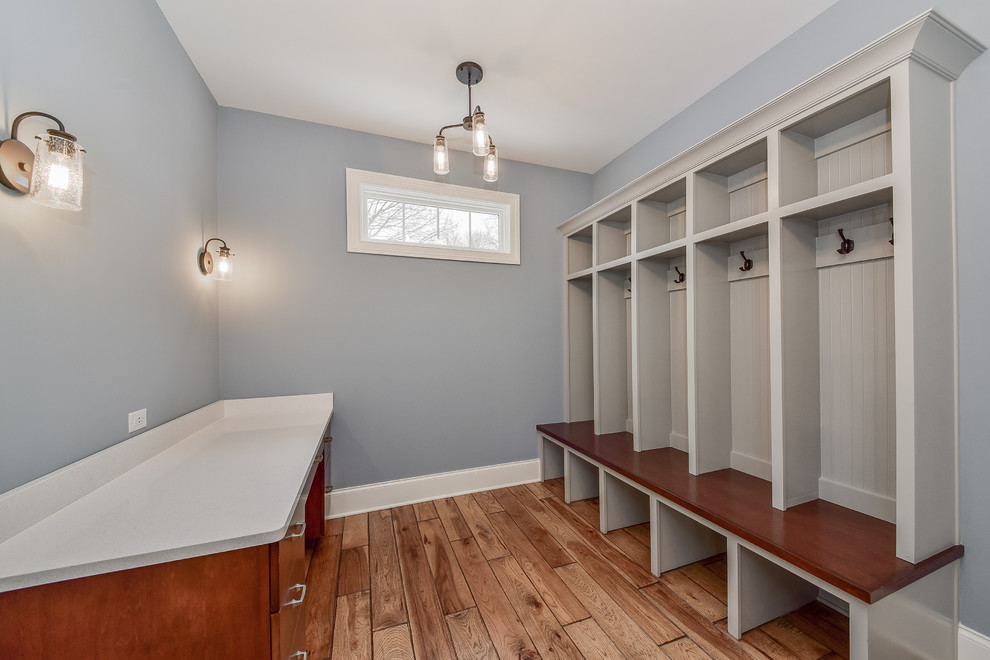 This is an example of a mid-sized transitional mudroom in Chicago with grey walls, a single front door, a medium wood front door, laminate floors and brown floor.