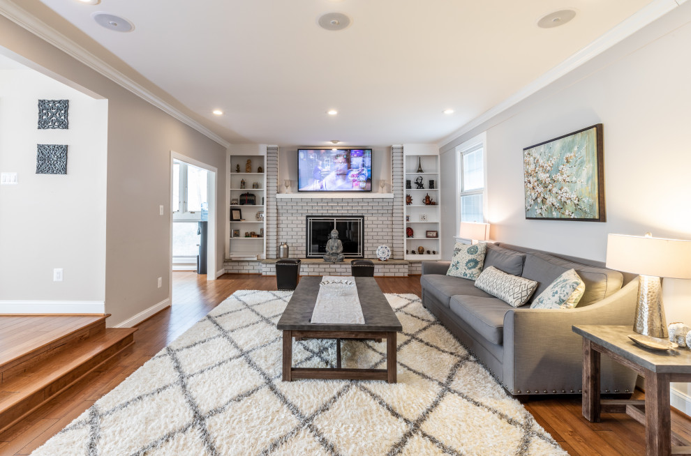 Photo of a small contemporary living room in DC Metro with a library, grey walls, light hardwood floors, a standard fireplace, a brick fireplace surround, a wall-mounted tv and beige floor.