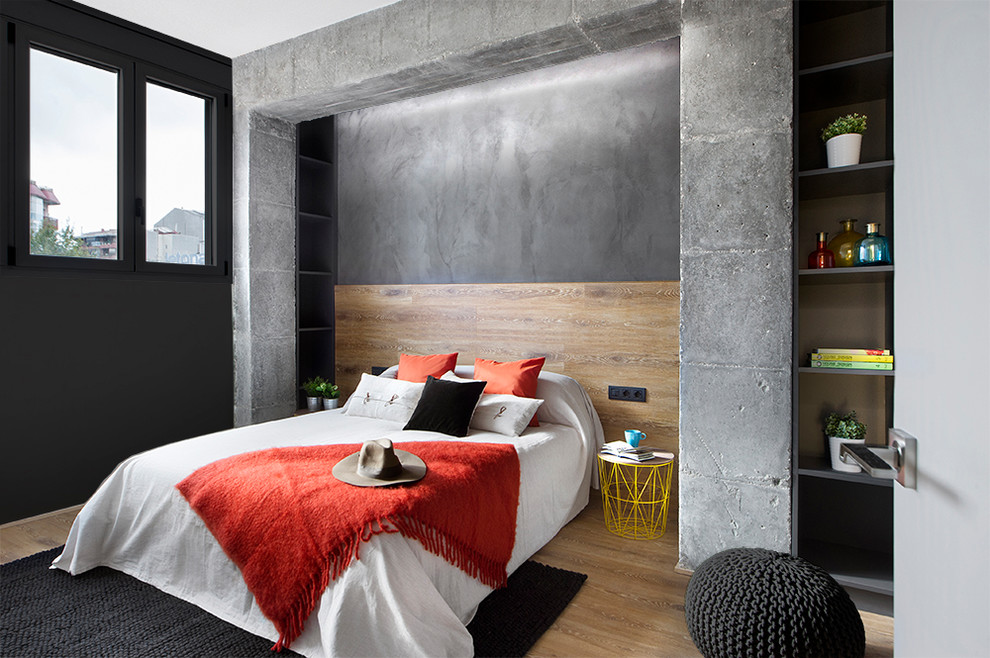 Design ideas for a mid-sized industrial master bedroom in Barcelona with grey walls, medium hardwood floors, no fireplace and brown floor.