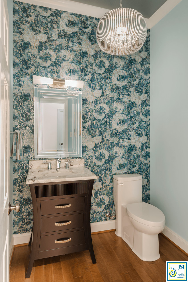 Exemple d'un petit WC et toilettes chic en bois foncé avec un placard en trompe-l'oeil, WC à poser, un mur bleu, un sol en bois brun, un lavabo encastré, un plan de toilette en marbre et un sol marron.