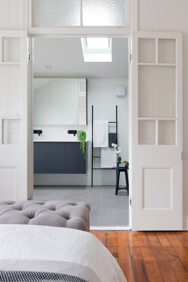 This is an example of a beach style master bathroom in Brisbane with flat-panel cabinets, black cabinets, white walls, grey floor and white benchtops.