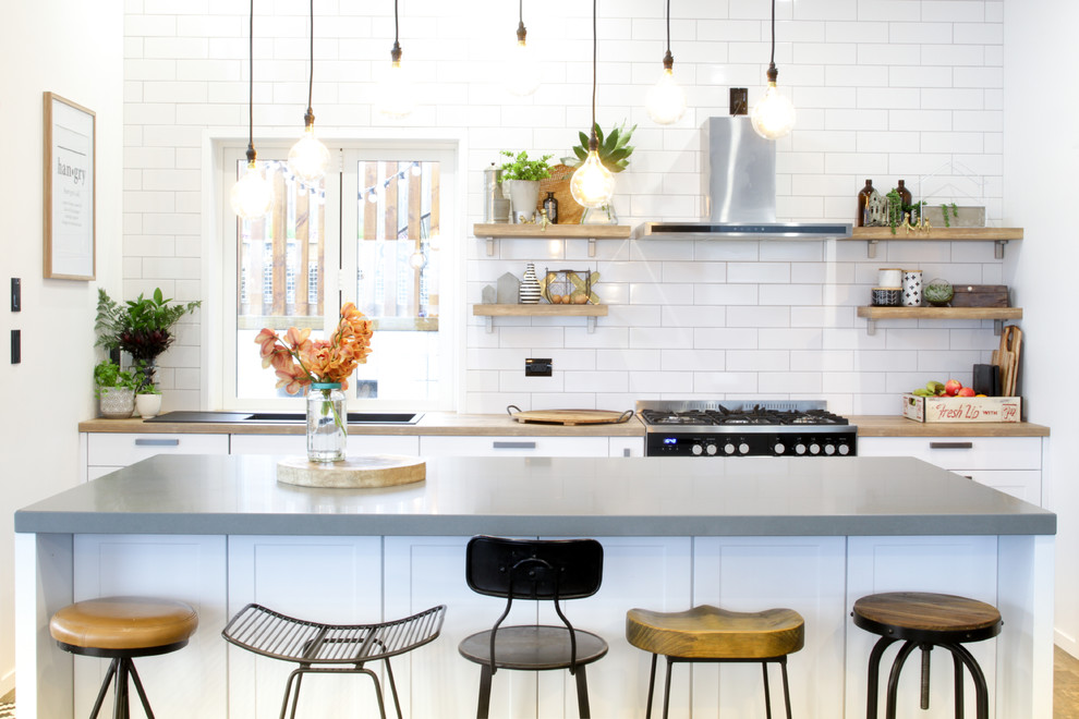 Design ideas for a mid-sized eclectic single-wall kitchen in Other with shaker cabinets, white cabinets, laminate benchtops, white splashback, subway tile splashback, stainless steel appliances, laminate floors, with island, brown floor and a drop-in sink.