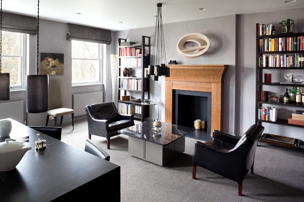 Photo of a contemporary open concept living room in London with a library, grey walls, carpet, a standard fireplace and no tv.