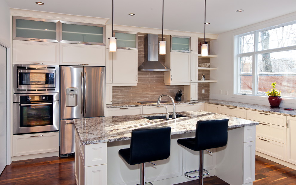 Inspiration for a mid-sized transitional l-shaped medium tone wood floor kitchen remodel in Montreal with an undermount sink, shaker cabinets, white cabinets, granite countertops, beige backsplash, stone tile backsplash, stainless steel appliances and an island