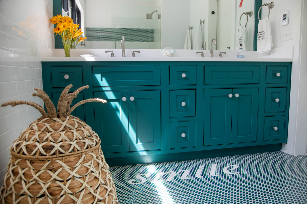 Photo of a mid-sized eclectic kids bathroom in Milwaukee with beaded inset cabinets, turquoise cabinets, an alcove tub, a two-piece toilet, white tile, cement tile, white walls, mosaic tile floors, an undermount sink, engineered quartz benchtops, turquoise floor, a hinged shower door, white benchtops, a niche, a double vanity and a built-in vanity.