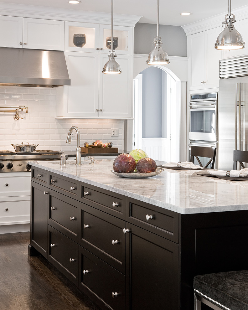 This is an example of a traditional kitchen in Boston with stainless steel appliances, granite benchtops, recessed-panel cabinets, white cabinets, white splashback, subway tile splashback and white benchtop.