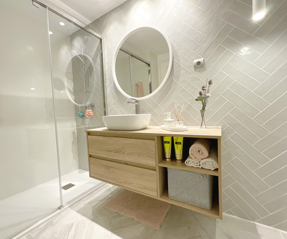 Idéer för ett mellanstort modernt beige badrum, med släta luckor, vita skåp, en dusch i en alkov, en vägghängd toalettstol, grå kakel, keramikplattor, vita väggar, klinkergolv i porslin, ett fristående handfat, laminatbänkskiva, grått golv och dusch med skjutdörr