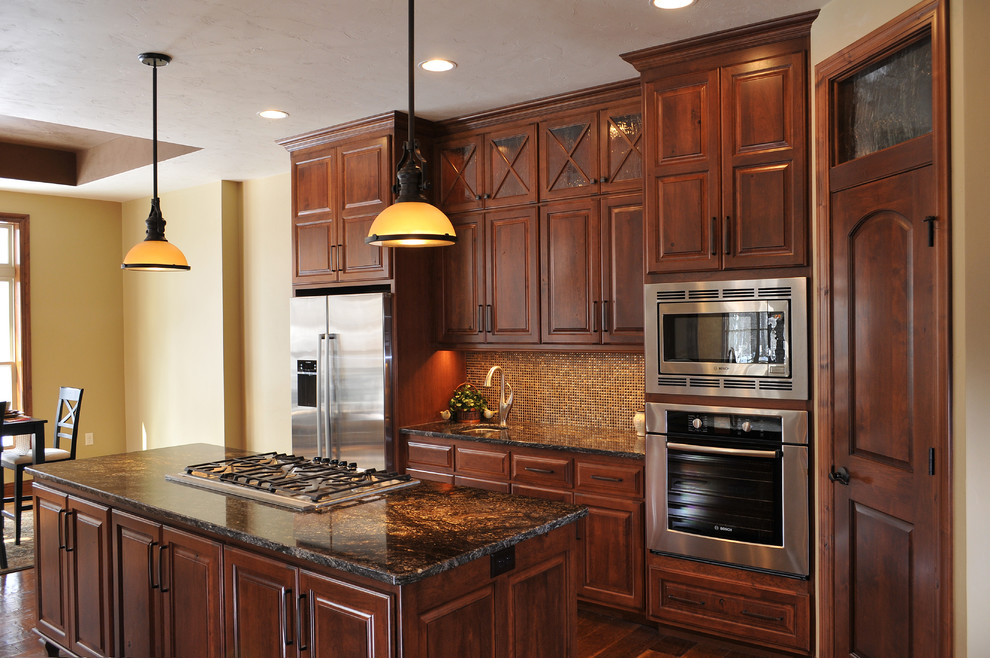 This is an example of a large contemporary l-shaped eat-in kitchen in Milwaukee with an undermount sink, granite benchtops, stainless steel appliances, medium hardwood floors, with island, raised-panel cabinets, dark wood cabinets, brown splashback and mosaic tile splashback.