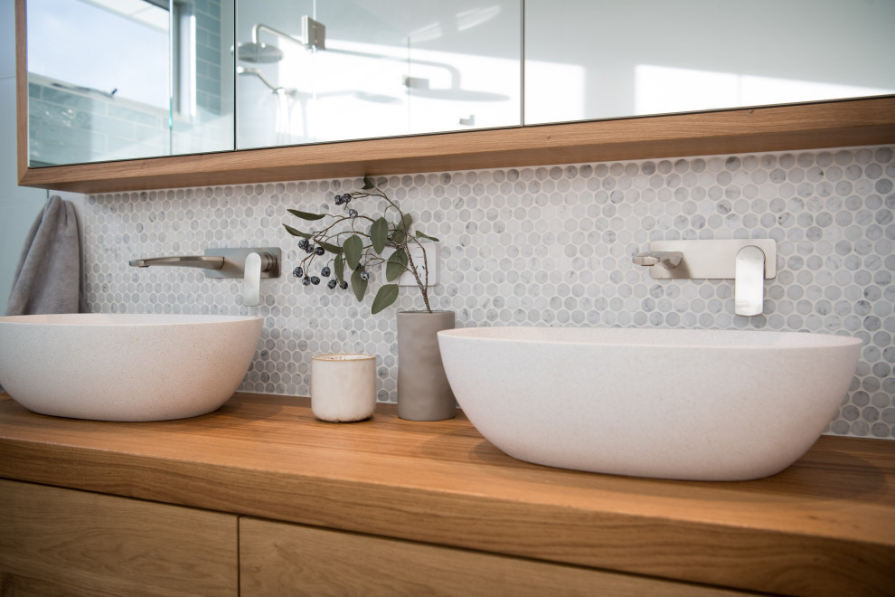 This is an example of a large beach style master bathroom in Wollongong with open cabinets, medium wood cabinets, a freestanding tub, a corner shower, beige tile, porcelain tile, beige walls, porcelain floors, a vessel sink, wood benchtops, beige floor, a hinged shower door, brown benchtops and a double vanity.