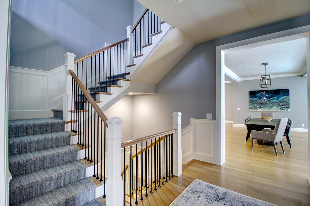 Huge transitional wooden u-shaped mixed material railing and wainscoting staircase photo in Denver with wooden risers