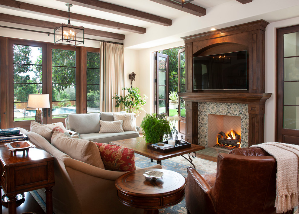 Photo of a mediterranean family room in San Diego with white walls, a built-in media wall, a standard fireplace and a tile fireplace surround.