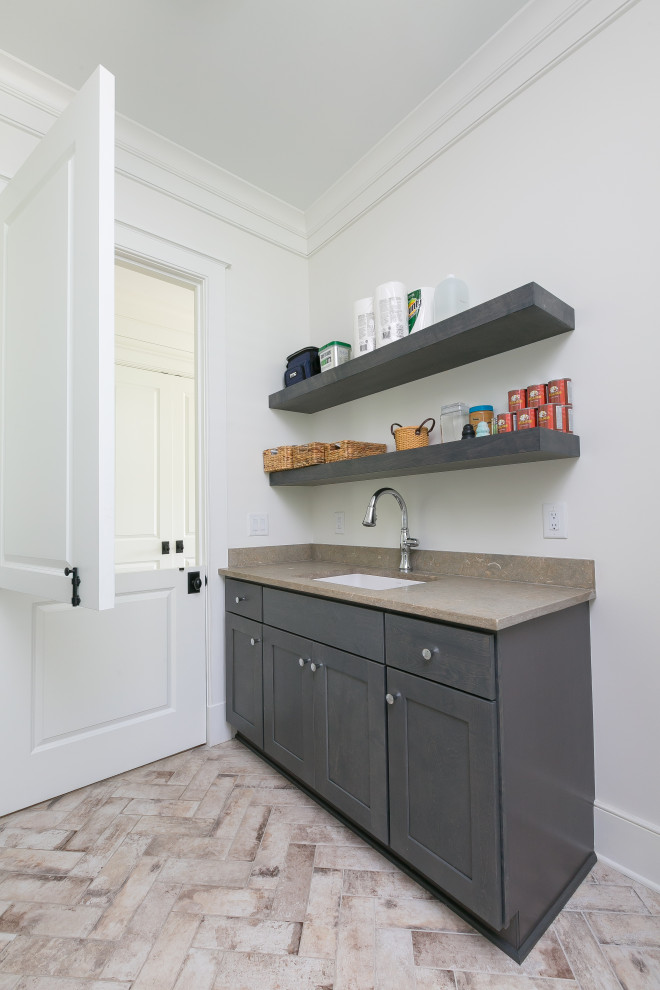 This is an example of a mid-sized transitional galley dedicated laundry room in Charleston with an undermount sink, shaker cabinets, dark wood cabinets, quartz benchtops, beige walls, porcelain floors, a side-by-side washer and dryer, multi-coloured floor and beige benchtop.