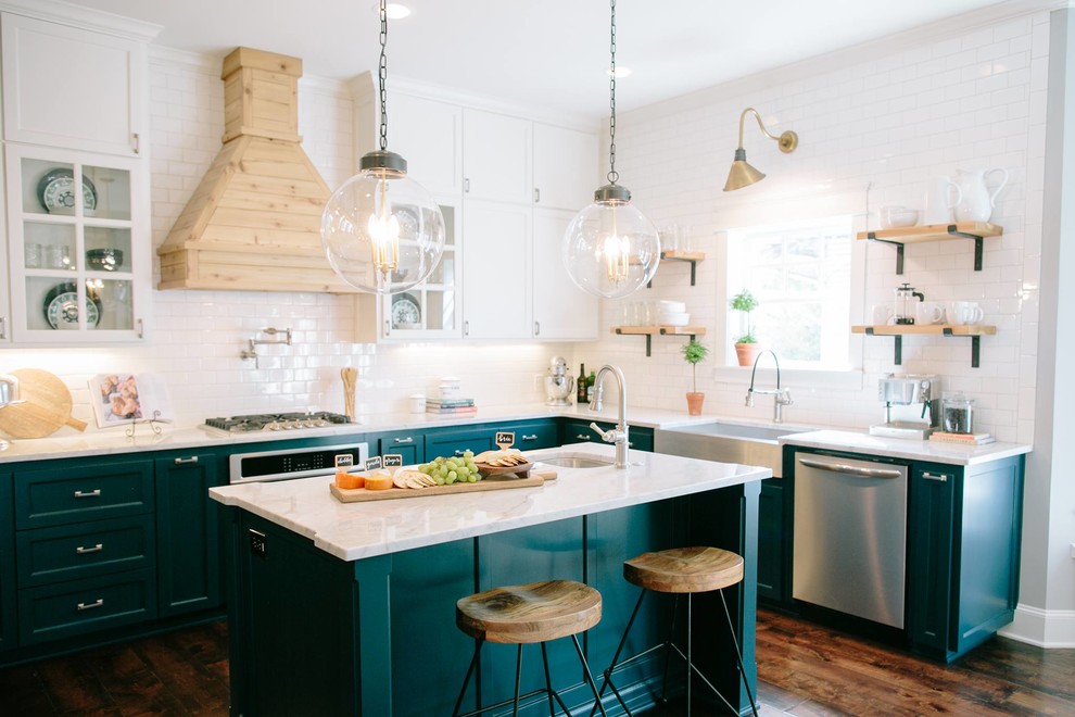 Photo of a transitional l-shaped kitchen in Austin with a farmhouse sink, recessed-panel cabinets, green cabinets, white splashback, subway tile splashback, stainless steel appliances, dark hardwood floors and with island.