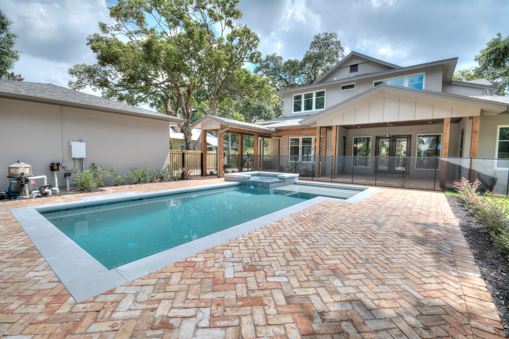 This is an example of a mid-sized traditional backyard rectangular lap pool in Orlando with brick pavers and a hot tub.