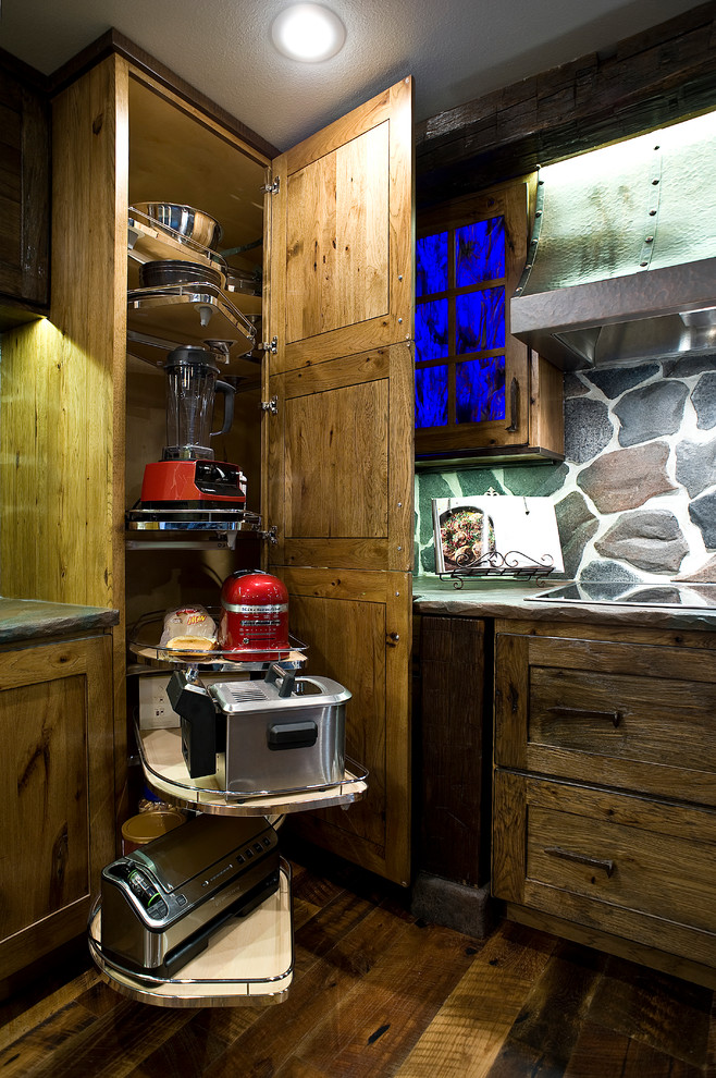 Mid-sized mountain style l-shaped medium tone wood floor eat-in kitchen photo with a farmhouse sink, shaker cabinets, distressed cabinets, concrete countertops, gray backsplash, stone slab backsplash, stainless steel appliances and an island