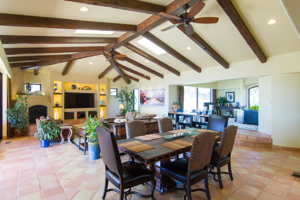 Photo of a mid-sized mediterranean enclosed family room in San Luis Obispo with beige walls, terra-cotta floors, a standard fireplace, a plaster fireplace surround and a built-in media wall.