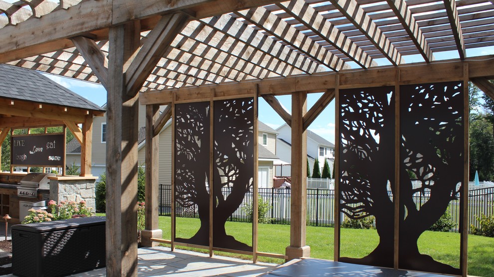 Photo of a mid-sized country backyard patio in Boston with natural stone pavers and a pergola.