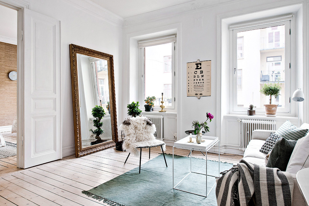 Scandinavian formal enclosed living room in Gothenburg with white walls, light hardwood floors, no fireplace and no tv.