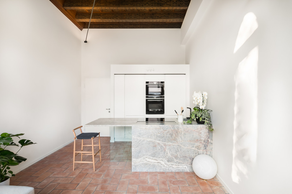 Photo of a mid-sized contemporary galley open plan kitchen in Other with an undermount sink, recessed-panel cabinets, white cabinets, marble benchtops, marble floors, a peninsula, red floor, multi-coloured benchtop and coffered.