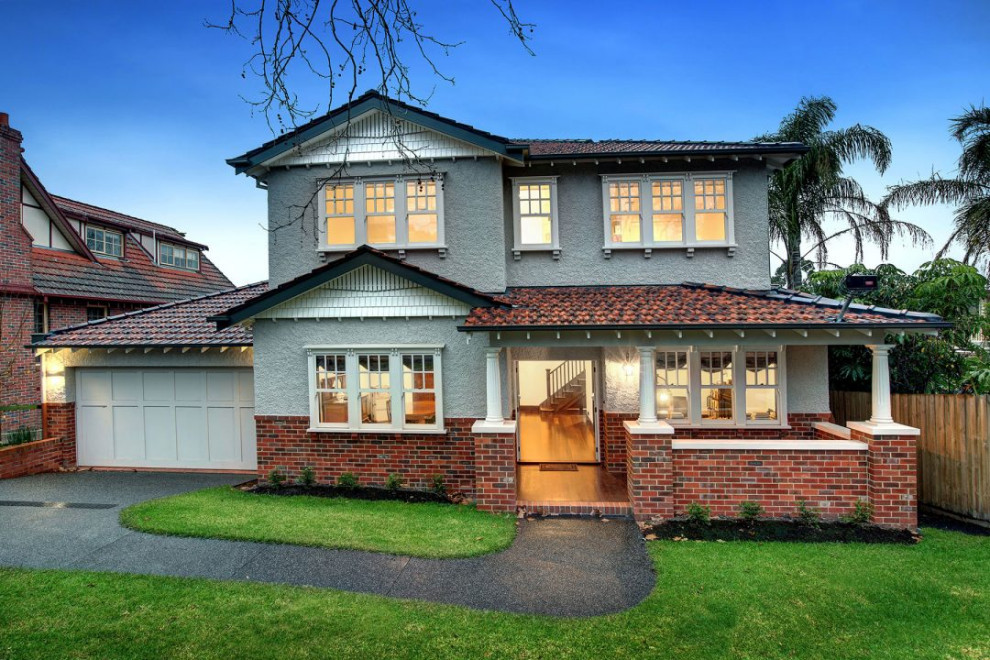 Photo of a traditional two-storey stucco beige house exterior in Melbourne with a gable roof, a tile roof, a red roof and shingle siding.