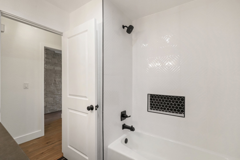 Exempel på ett mellanstort modernt svart svart badrum för barn, med skåp i shakerstil, vita skåp, ett badkar i en alkov, en dusch/badkar-kombination, en toalettstol med separat cisternkåpa, vita väggar, klinkergolv i keramik, ett undermonterad handfat, granitbänkskiva, svart golv och med dusch som är öppen