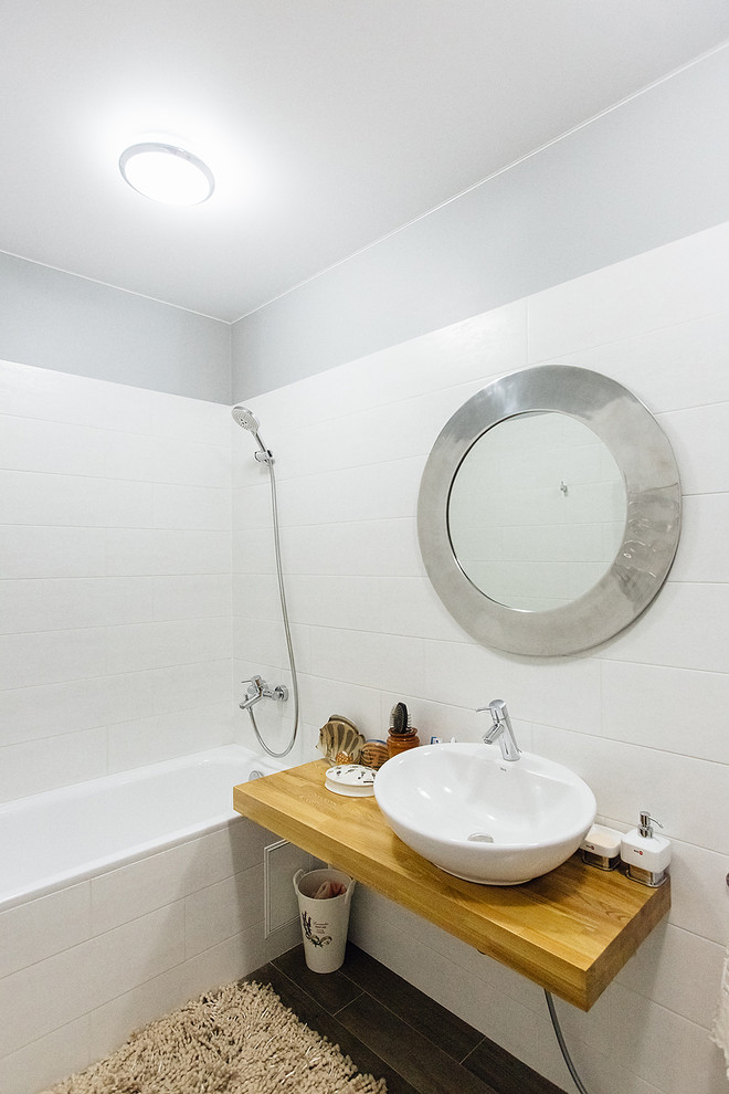 Photo of a small scandinavian bathroom in Other with an alcove tub, a shower/bathtub combo, white tile, ceramic tile, grey walls, porcelain floors, a drop-in sink, wood benchtops and grey floor.