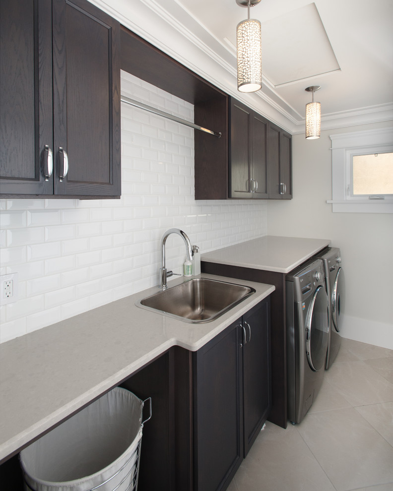 Mid-sized arts and crafts single-wall dedicated laundry room in Vancouver with a drop-in sink, dark wood cabinets, white walls, a side-by-side washer and dryer and recessed-panel cabinets.