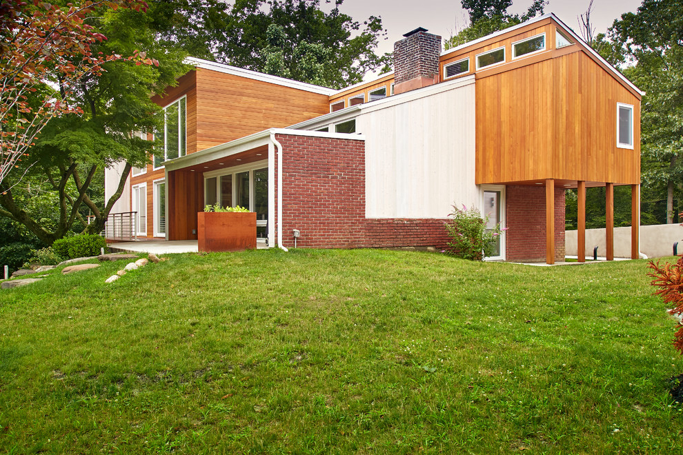 Photo of a mid-sized modern two-storey multi-coloured house exterior in New York with wood siding, a shed roof and a mixed roof.