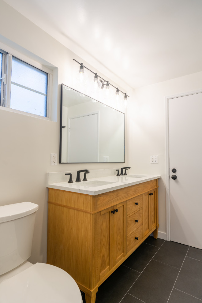 This is an example of a small modern master bathroom in Los Angeles with shaker cabinets, light wood cabinets, an alcove shower, a one-piece toilet, green tile, ceramic tile, white walls, concrete floors, a drop-in sink, marble benchtops, black floor, a hinged shower door, white benchtops, a double vanity and a freestanding vanity.