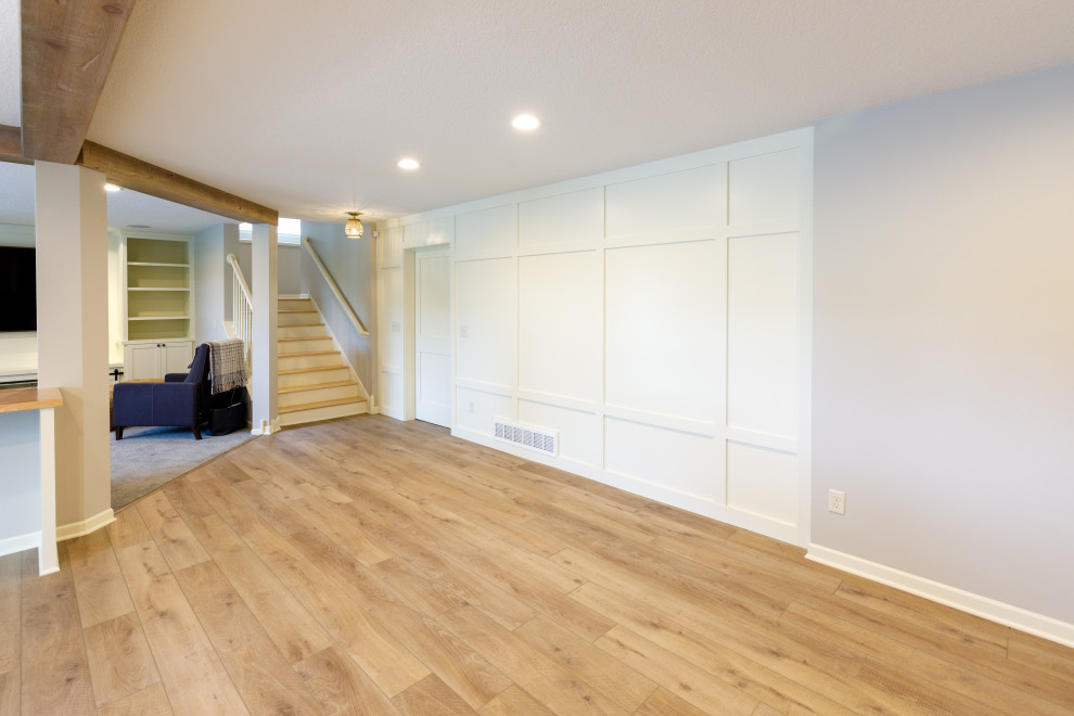 Large traditional walk-out basement in Minneapolis with a home bar, grey walls, vinyl flooring, brown floors and exposed beams.