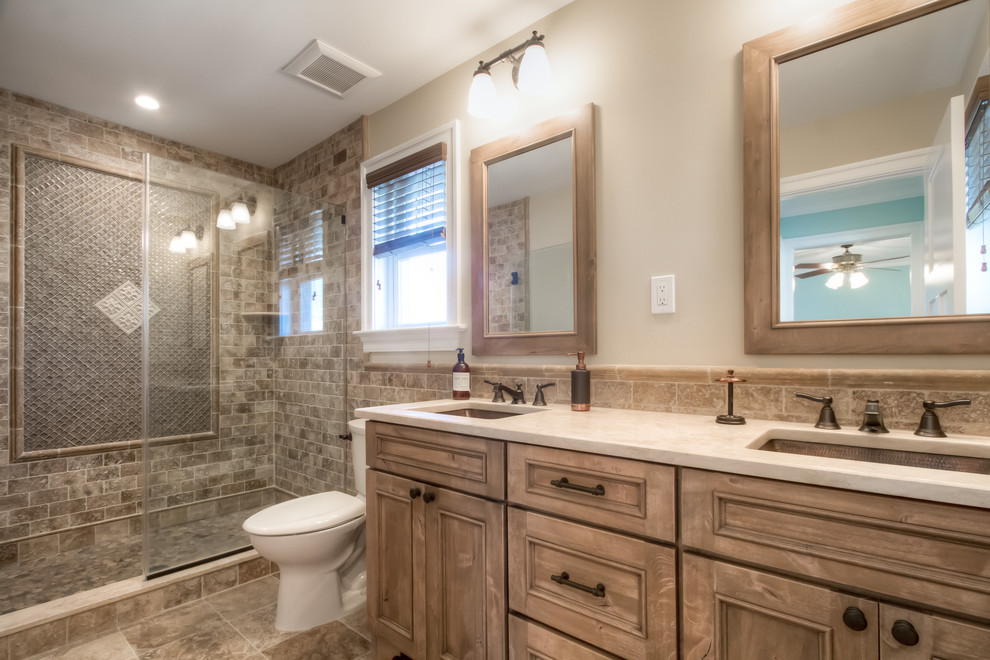 Inspiration for a mid-sized traditional master bathroom in Philadelphia with recessed-panel cabinets, medium wood cabinets, an alcove shower, beige tile, brown tile, stone tile, beige walls, porcelain floors, an undermount sink and solid surface benchtops.
