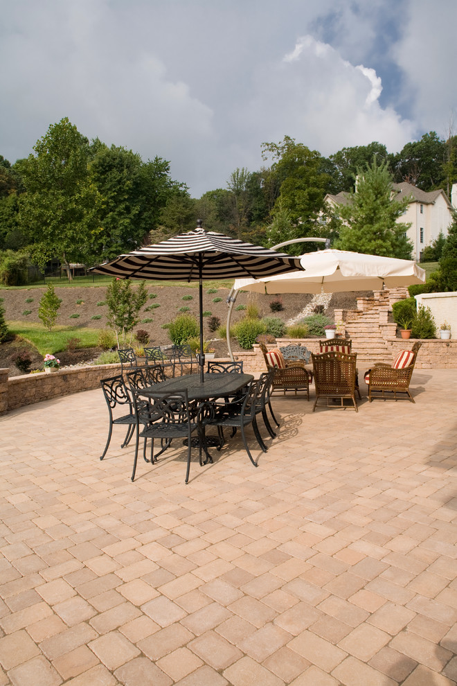 This is an example of a mid-sized traditional backyard patio in Philadelphia with an outdoor kitchen, concrete pavers and an awning.