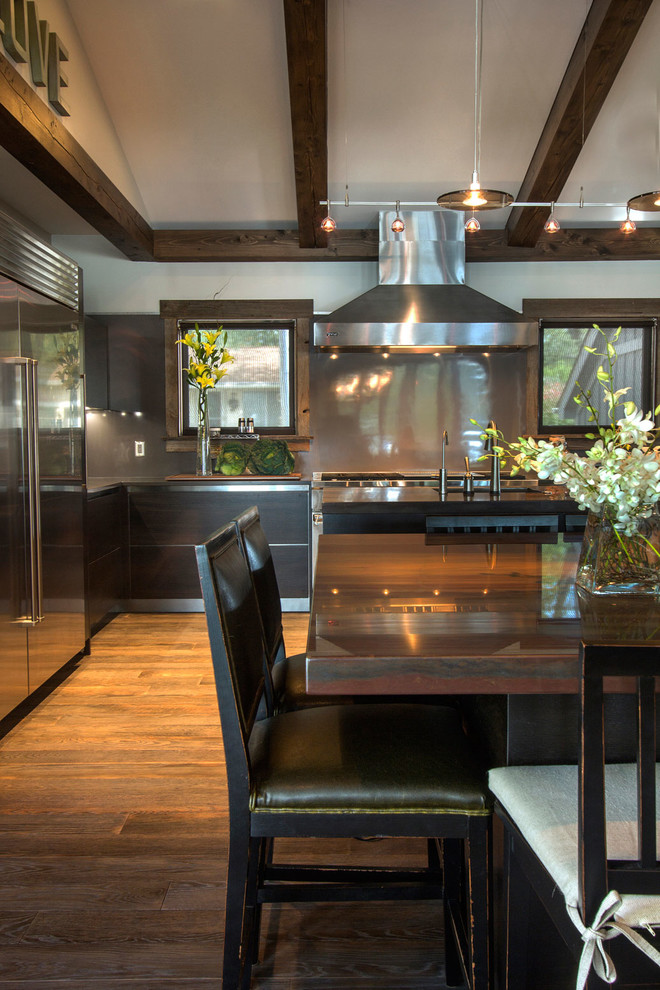 Example of a large transitional l-shaped medium tone wood floor and brown floor eat-in kitchen design with quartzite countertops, an undermount sink, flat-panel cabinets, dark wood cabinets, stainless steel appliances and two islands