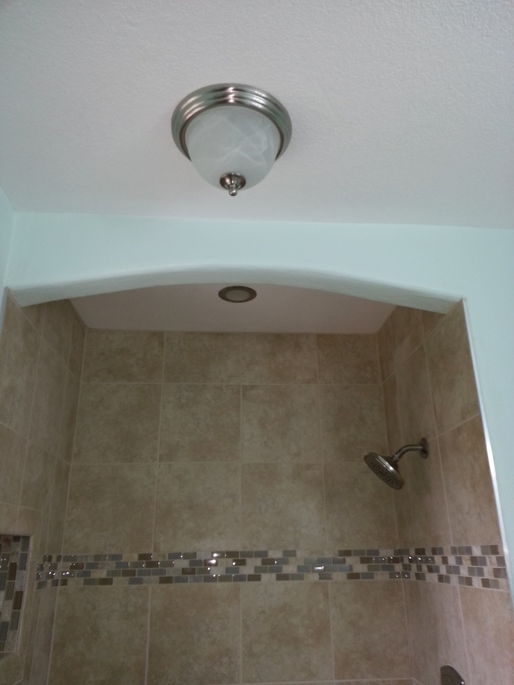Alcove shower - mid-sized transitional 3/4 beige tile and porcelain tile porcelain tile and beige floor alcove shower idea with raised-panel cabinets, white cabinets, a two-piece toilet, blue walls, an undermount sink, laminate countertops, a hinged shower door and multicolored countertops