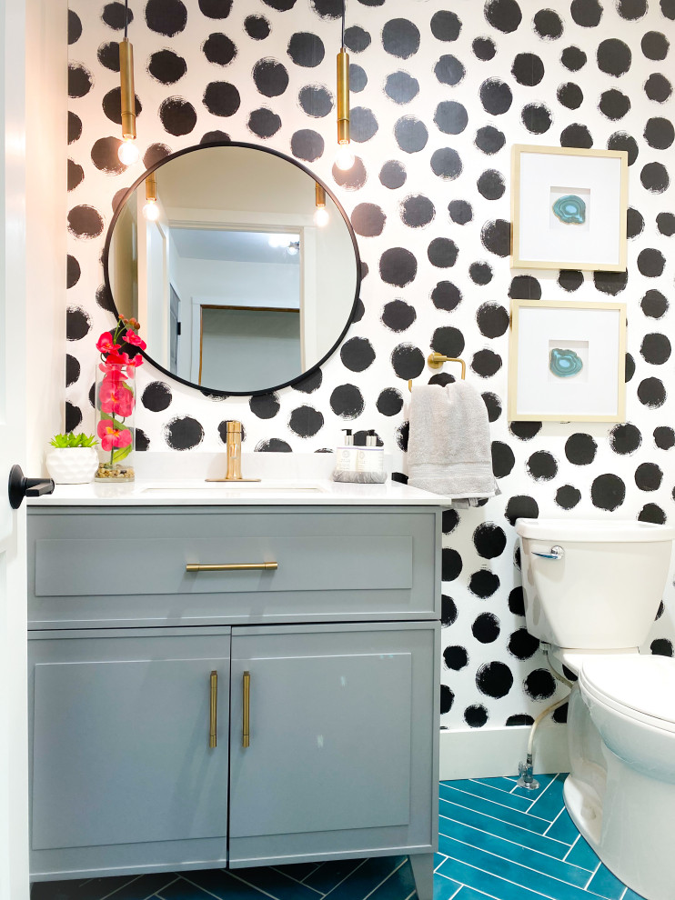 Design ideas for a small modern powder room in Other with raised-panel cabinets, grey cabinets, a two-piece toilet, white walls, ceramic floors, an undermount sink, engineered quartz benchtops, blue floor, white benchtops, a freestanding vanity and wallpaper.
