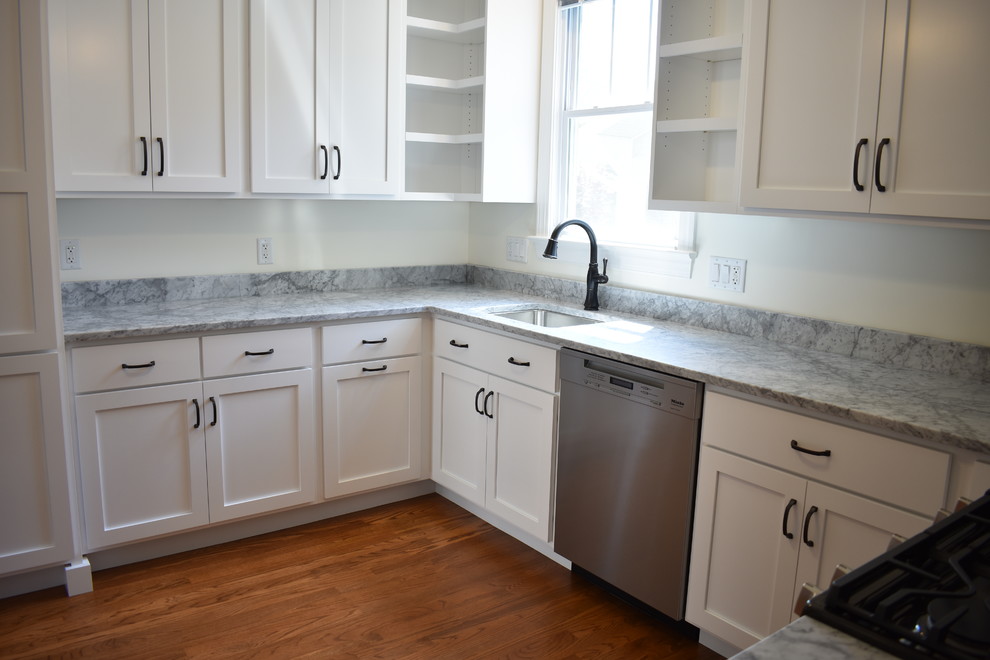 Mid-sized transitional u-shaped medium tone wood floor and brown floor home design photo with an undermount sink, recessed-panel cabinets, white cabinets, marble countertops, stainless steel appliances, no island and multicolored countertops