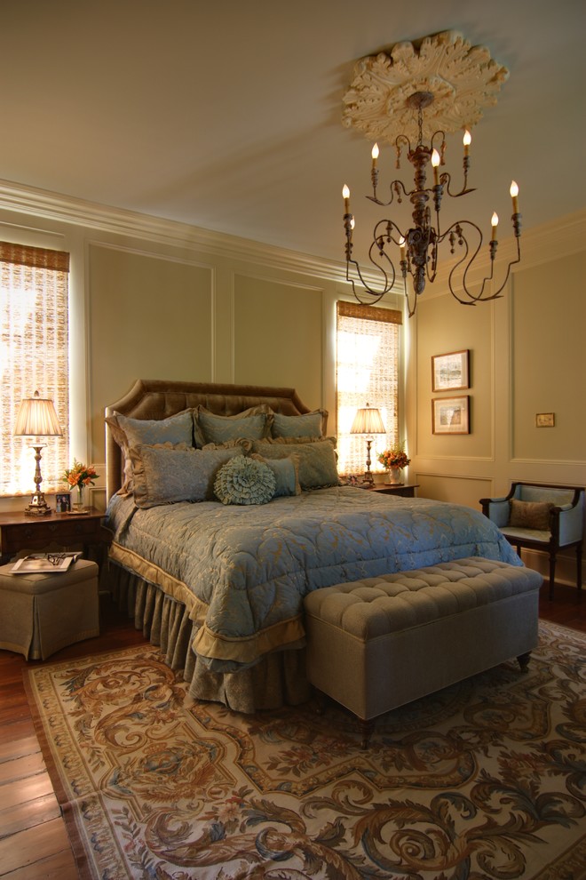 This is an example of a mid-sized traditional master bedroom in New Orleans with beige walls, dark hardwood floors and brown floor.