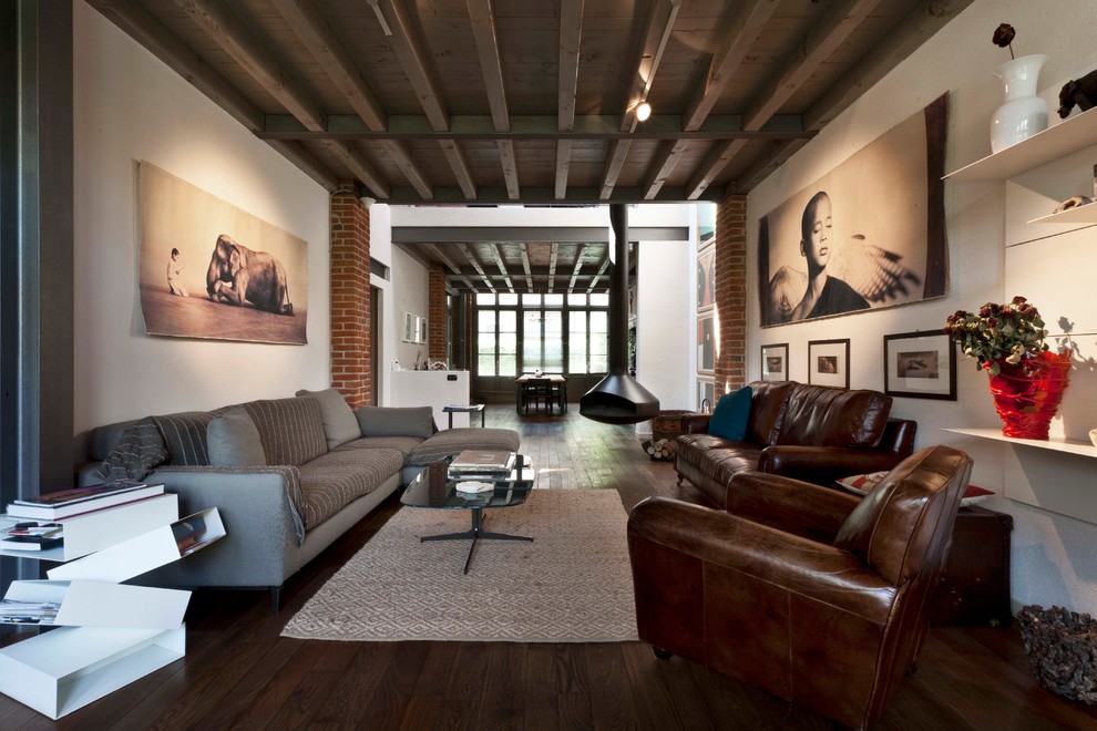Contemporary formal open concept living room in Milan with white walls, dark hardwood floors and a hanging fireplace.