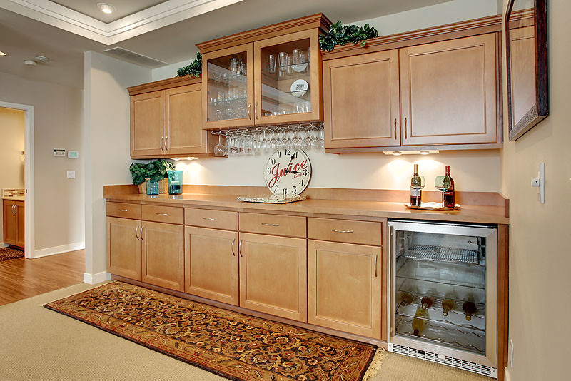 Photo of a mid-sized transitional single-wall home bar in Seattle with beaded inset cabinets, medium wood cabinets, wood benchtops, brown splashback and carpet.
