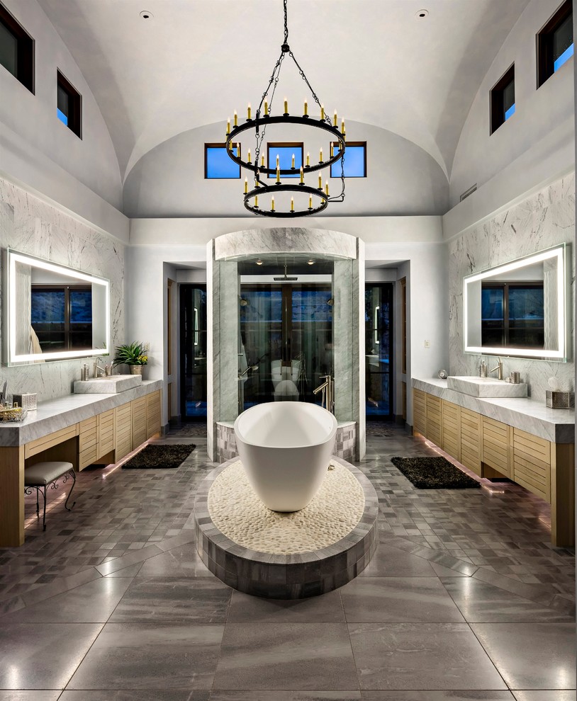 Inspiration for a contemporary master bathroom in Phoenix with flat-panel cabinets, light wood cabinets, a freestanding tub, black tile, gray tile, grey walls and a vessel sink.
