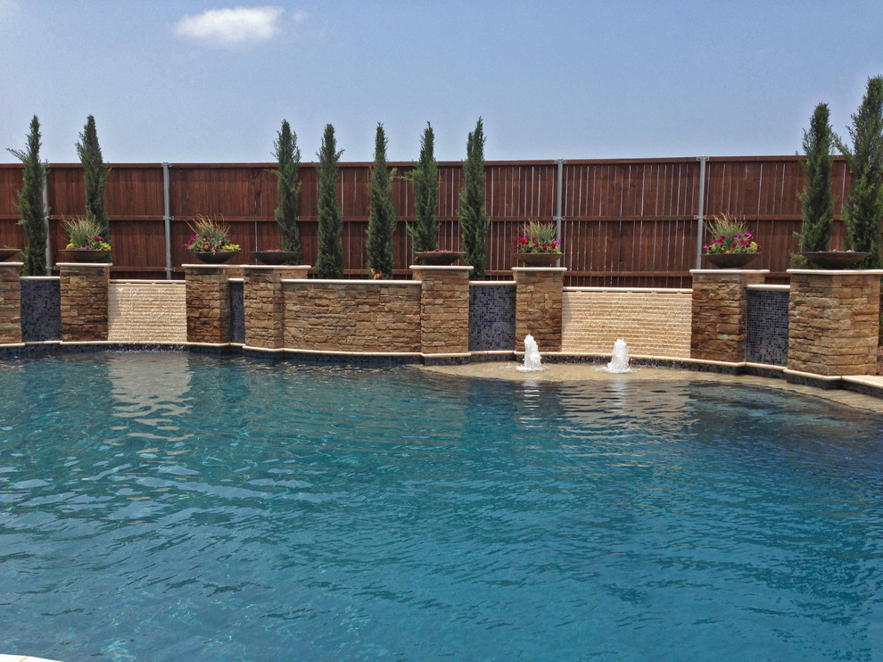 Design ideas for a large modern backyard custom-shaped lap pool in Dallas with a water feature and natural stone pavers.