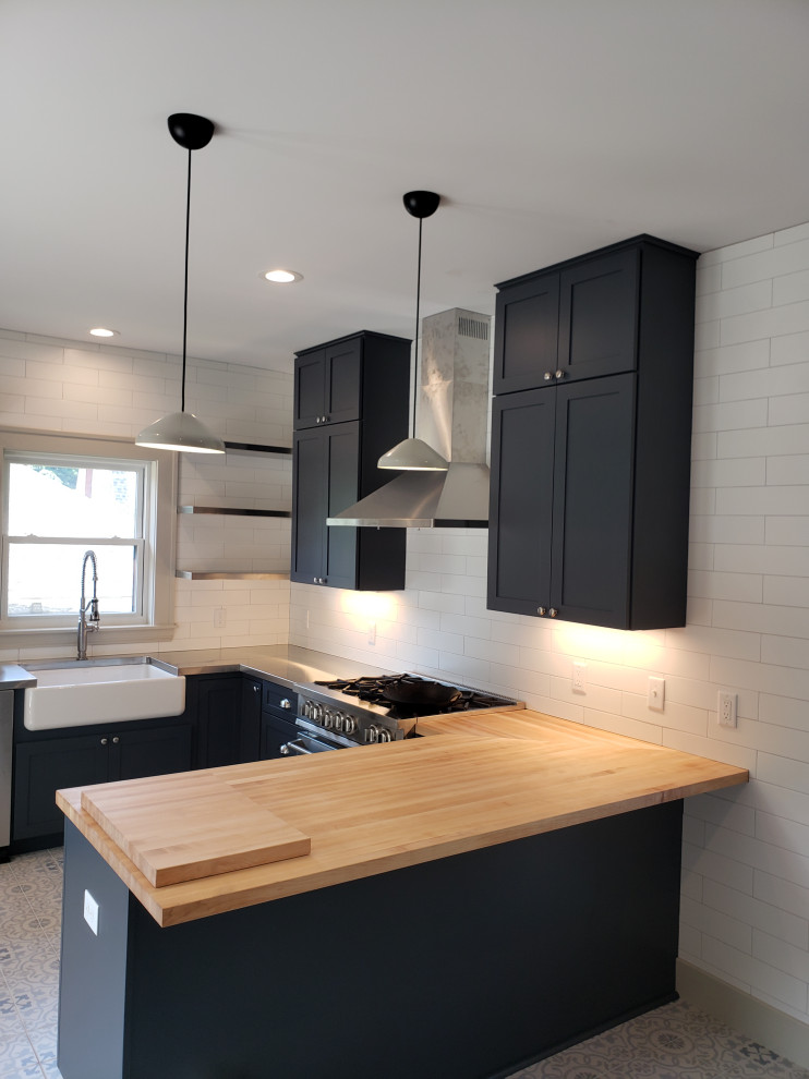 Design ideas for a large modern u-shaped separate kitchen in Grand Rapids with a farmhouse sink, shaker cabinets, blue cabinets, wood benchtops, white splashback, subway tile splashback, stainless steel appliances, porcelain floors, a peninsula and multi-coloured floor.