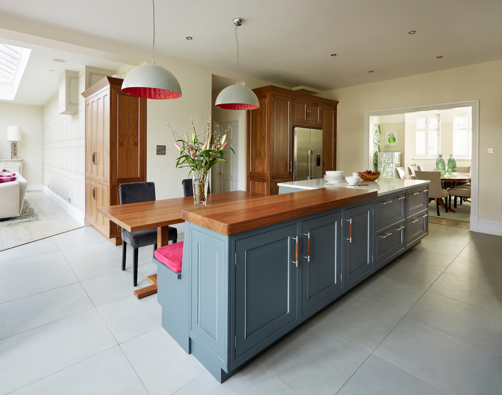 Large transitional eat-in kitchen in London with grey cabinets, wood benchtops, glass sheet splashback, stainless steel appliances and with island.