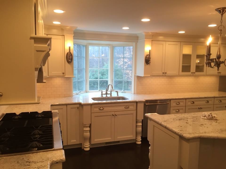 Example of a transitional u-shaped dark wood floor kitchen design in New York with an undermount sink, recessed-panel cabinets, white cabinets, granite countertops, white backsplash, subway tile backsplash, stainless steel appliances and an island