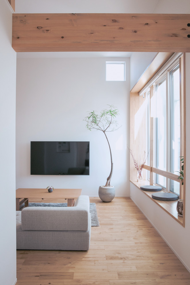 Idée de décoration pour un salon design avec un mur blanc, parquet clair, un téléviseur fixé au mur et un sol beige.